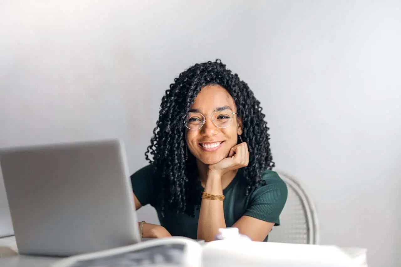 Woman smiling at work with laptop, diverse professional woman, modern office environment, engaging with technology, confident and happy, female entrepreneur, professional workspace, friendly businesswoman, productivity, empowerment, female empowerment, success, positive attitude, working remotely, online work, digital workplace, career development, professional growth, workplace diversity, female leadership, innovation, empowerment.