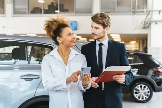 Meeting between a sales advisor and a customer at a car dealership, discussing vehicle options and financing, in a modern showroom environment.