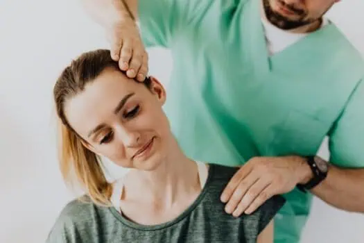 Chiropractic care provider performing spinal adjustment on female patient in a clinical setting.