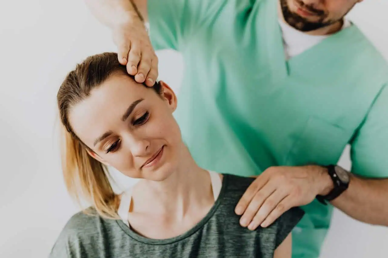 Chiropractic care provider performing spinal adjustment on female patient in a clinical setting.