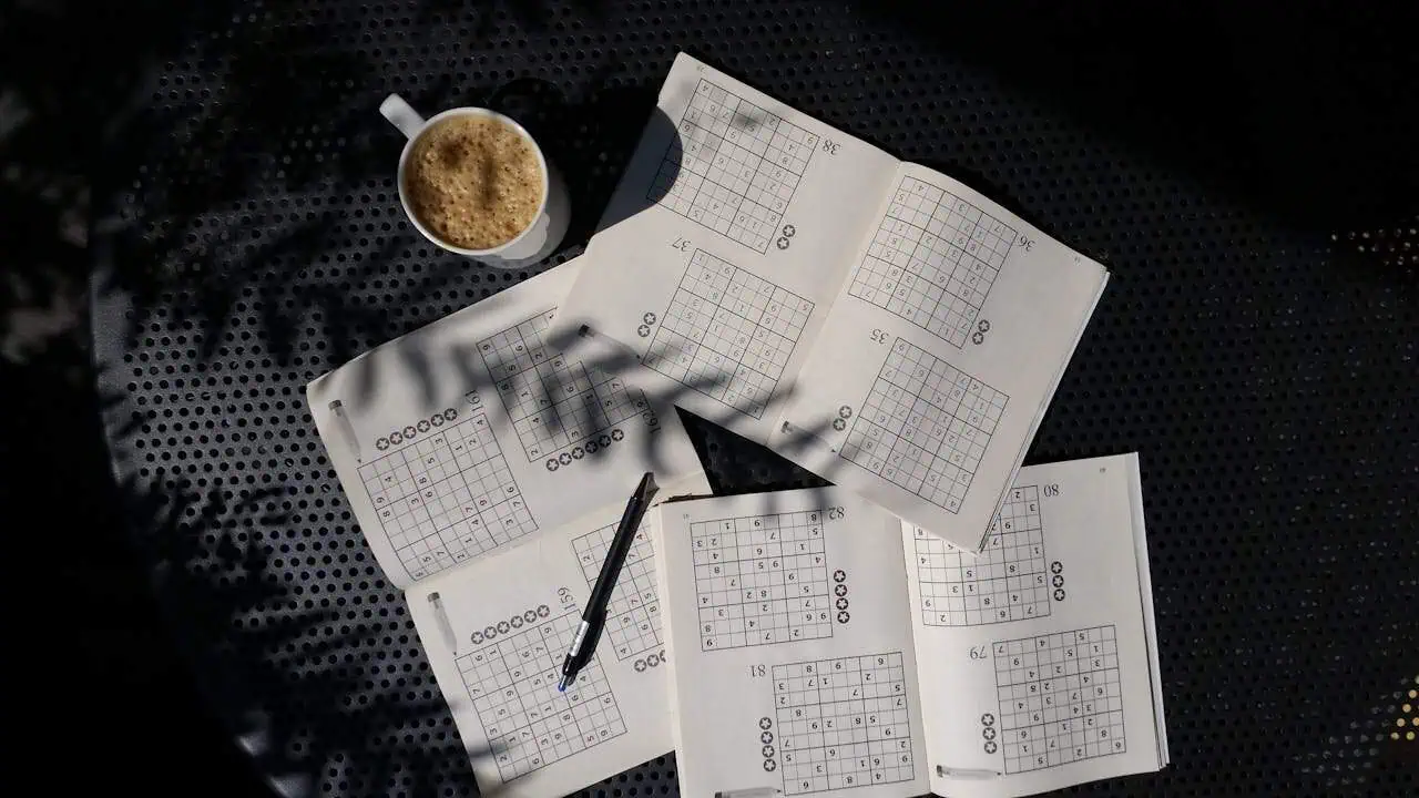 Sudoku puzzles with a cup of coffee on a black perforated surface, showcasing mental agility and concentration.