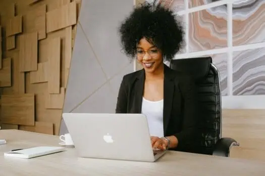 Optimised professional woman working on a laptop in modern office environment for diversity and inclusion at work.