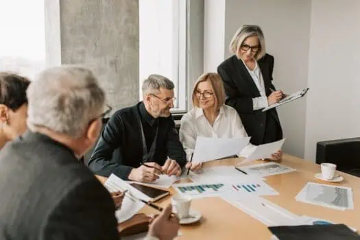 Business professionals discussing reports during a meeting in a modern office environment.