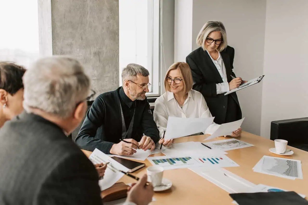 Business professionals discussing reports during a meeting in a modern office environment.
