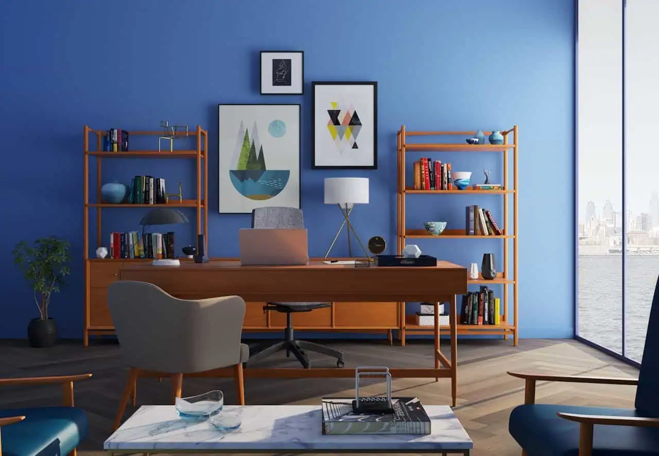 Modern office workspace with blue accent walls, wooden furniture, bookshelves, and scenic city view through floor-to-ceiling windows, creating a professional and inviting environment.