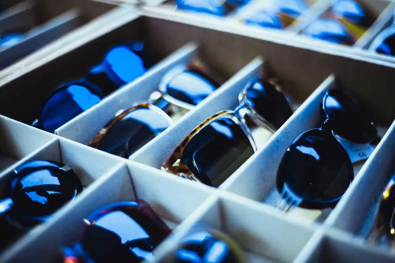 Colorful sunglasses arranged in a storage box for sale or display, showcasing a variety of styles. Perfect for summer fashion, outdoor activities, and accessories shopping.