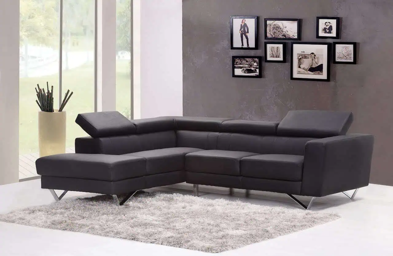 Black leather sectional sofa in modern living room with photo collage wall decor, large windows, and neutral colour scheme. Perfect for contemporary interior design and cosy family gatherings.