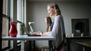 Secure working women using laptops in a modern office, promoting professional development and disability support services.