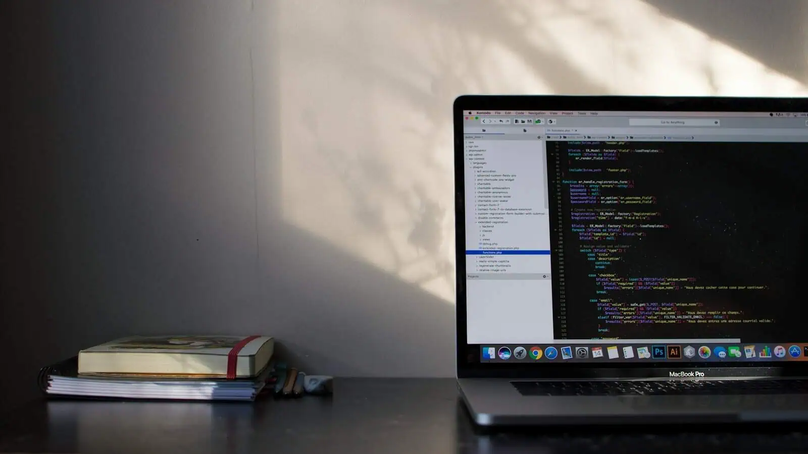 Coding on MacBook Pro with software development on screen, workspace with notebook and pens for programming, tech workspace.