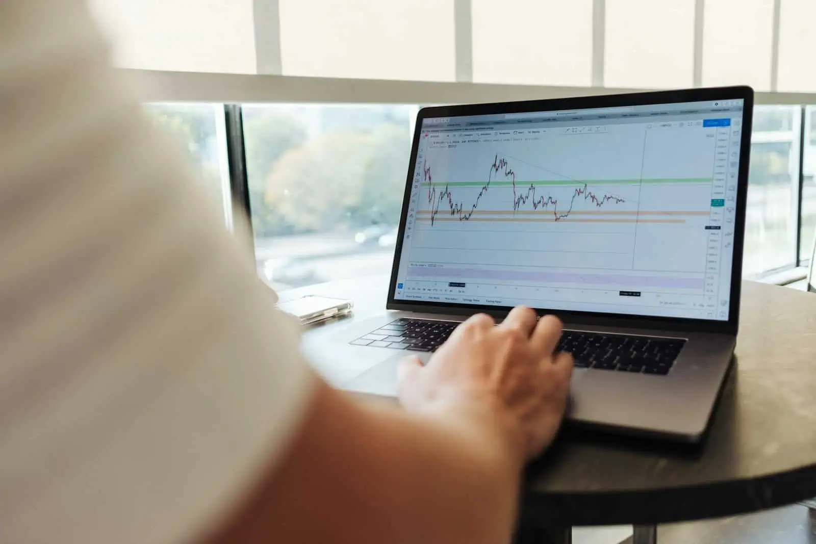 Stock trading and investment analysis on a laptop screen, showing financial graphs and charts, in a modern office setting.
