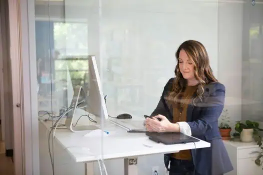 Accessible workplace for women, professional woman working on her smartphone at an office desk, promoting gender equality and diversity in the workplace.