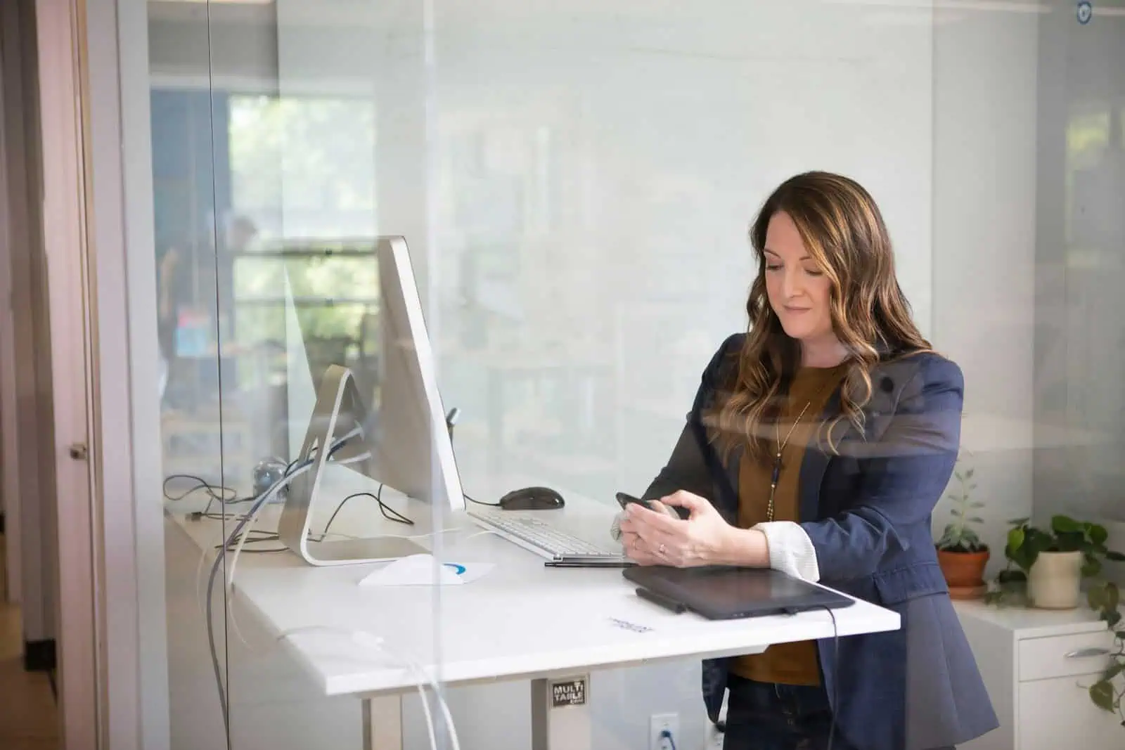 Accessible workplace for women, professional woman working on her smartphone at an office desk, promoting gender equality and diversity in the workplace.