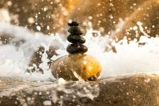 Balanced stone cairn on a beach shoreline, zen, meditation, mindfulness, relaxation, peaceful nature scene, wellness, self-care, harmony.