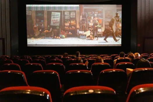 Audience watching a film scene depicting thrilling gambling moments on a large cinema screen.