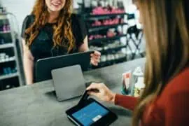 Customer making a contactless payment with a card at Prowess store, with a cashier assisting, in a retail environment.