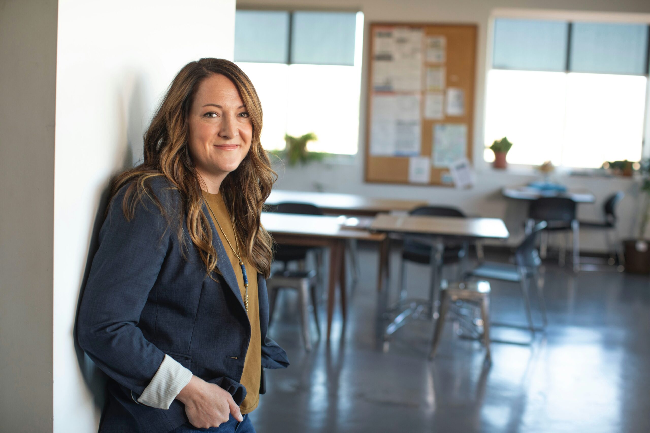 A woman in business attire leaning on a wall in the office