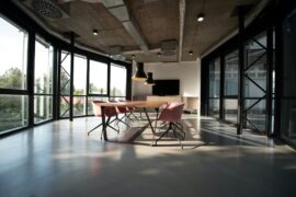 An empty large meeting room with a table, chairs and TV screen