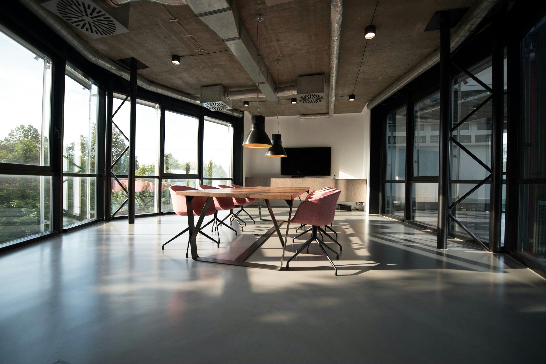 An empty large meeting room with a table, chairs and TV screen
