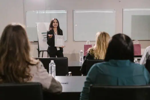 A woman presenting an award to an audience at the Women in Business Awards 2026, highlighting female achievement in UK business.