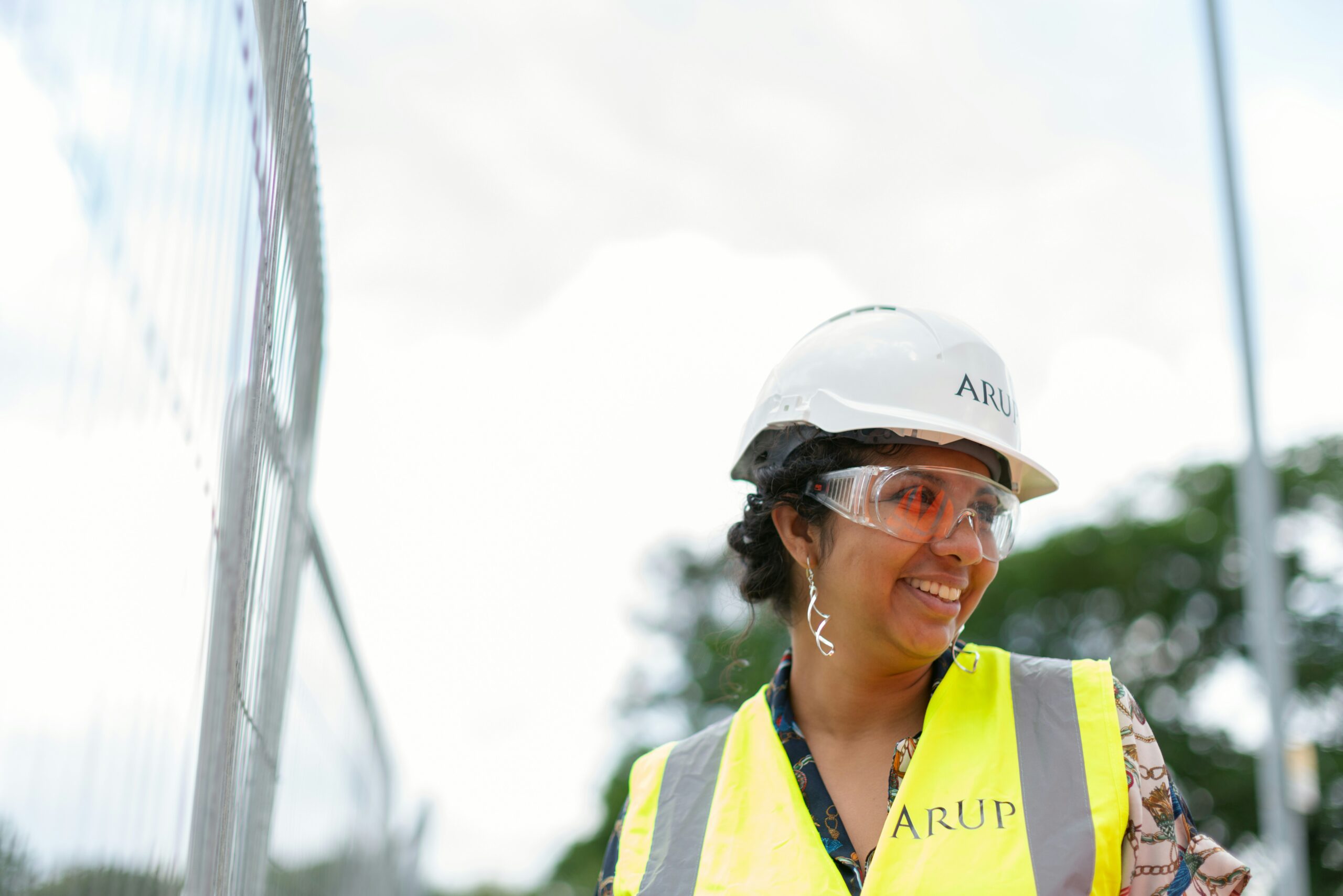 A tradeswoman going through the construction site in a helmet and smiling