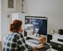 Woman sitting at home in front of the computer screen and thinking about what she sees