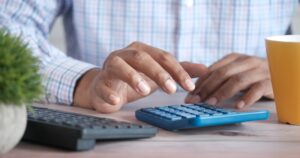 Close up of man hand using calculator.