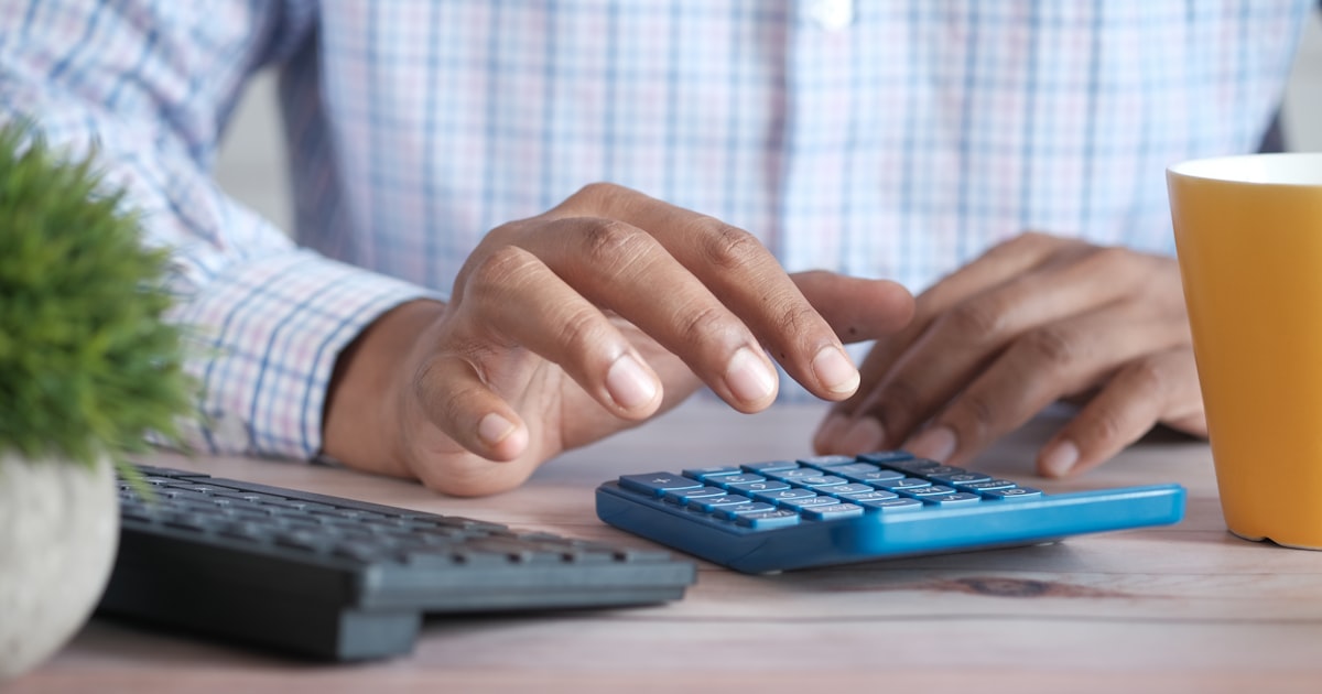 Close up of man hand using calculator.