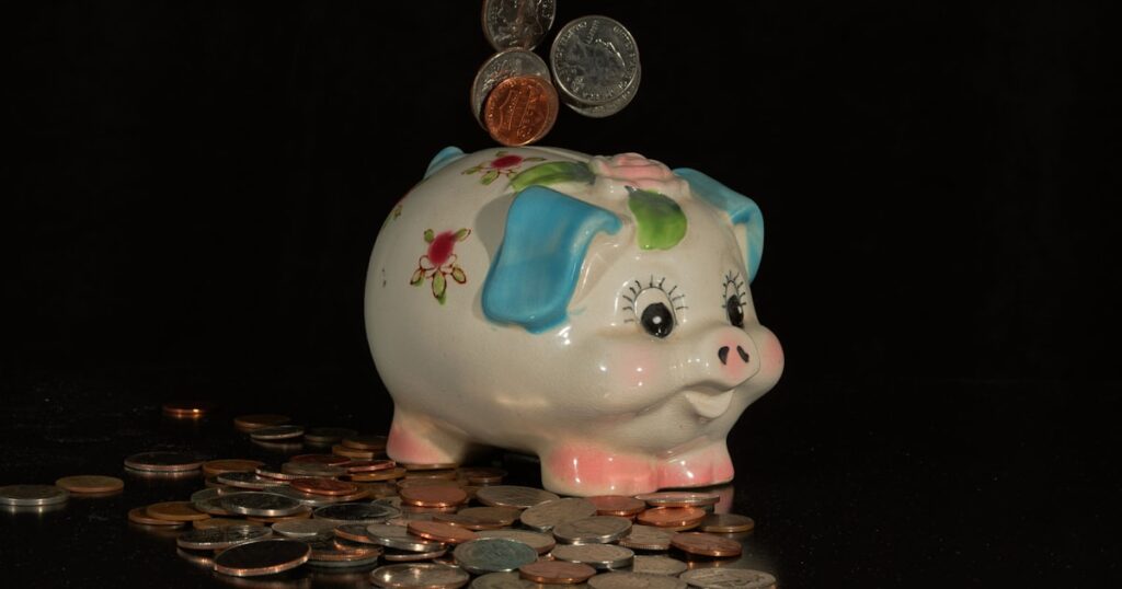 Coins falling into a piggy bank on a black background.