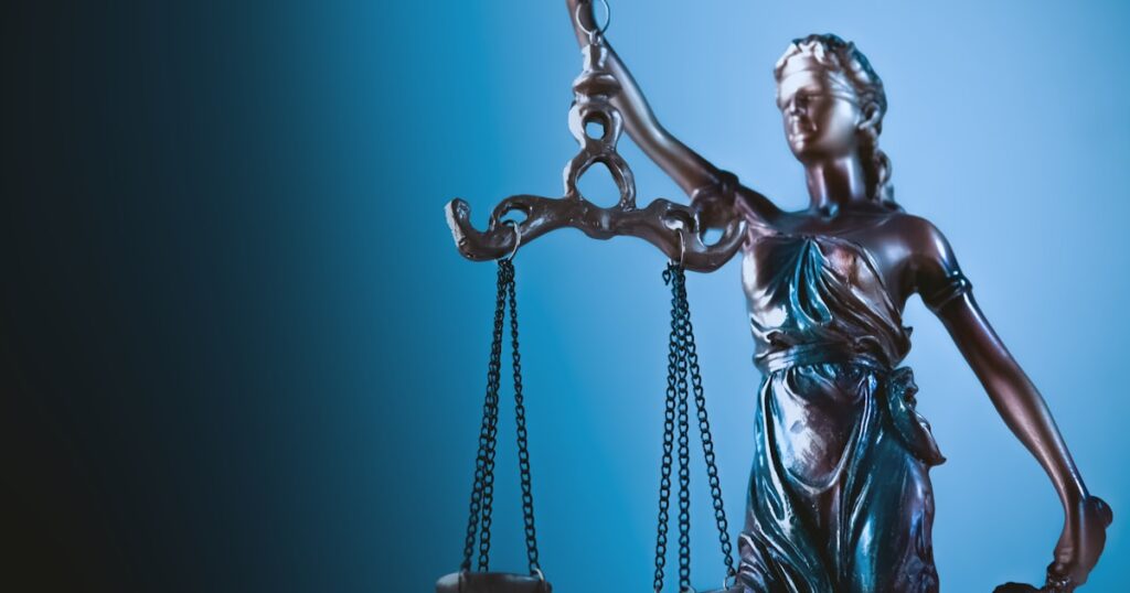 Statue of justice holding scales against blue background