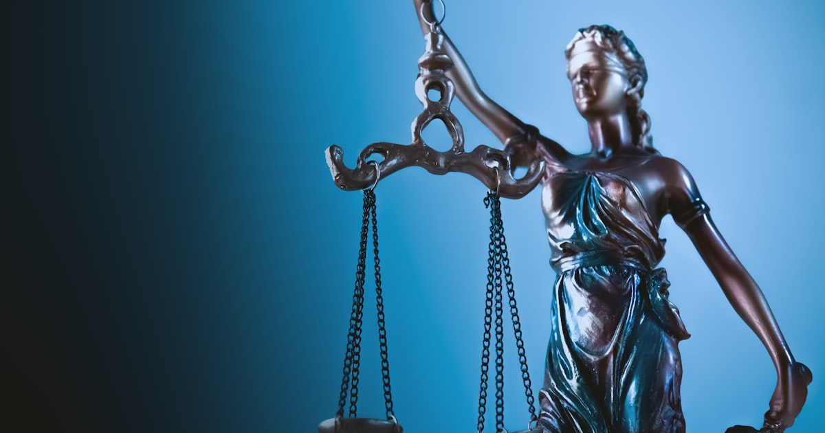 Statue of justice holding scales against blue background