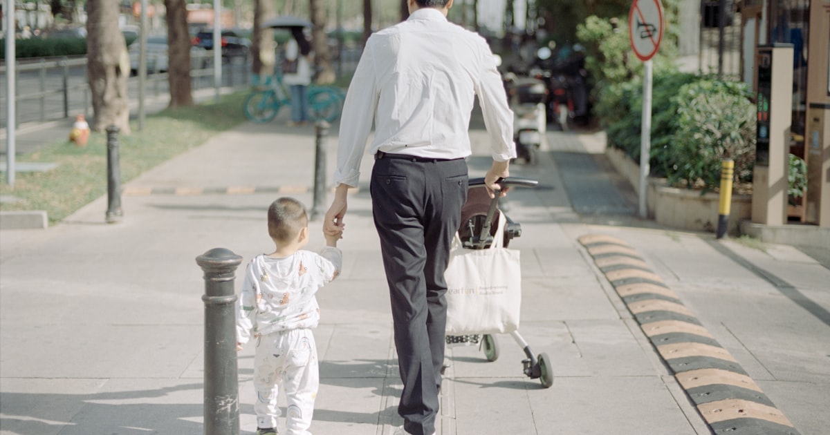 A father walks with his child down the sidewalk.