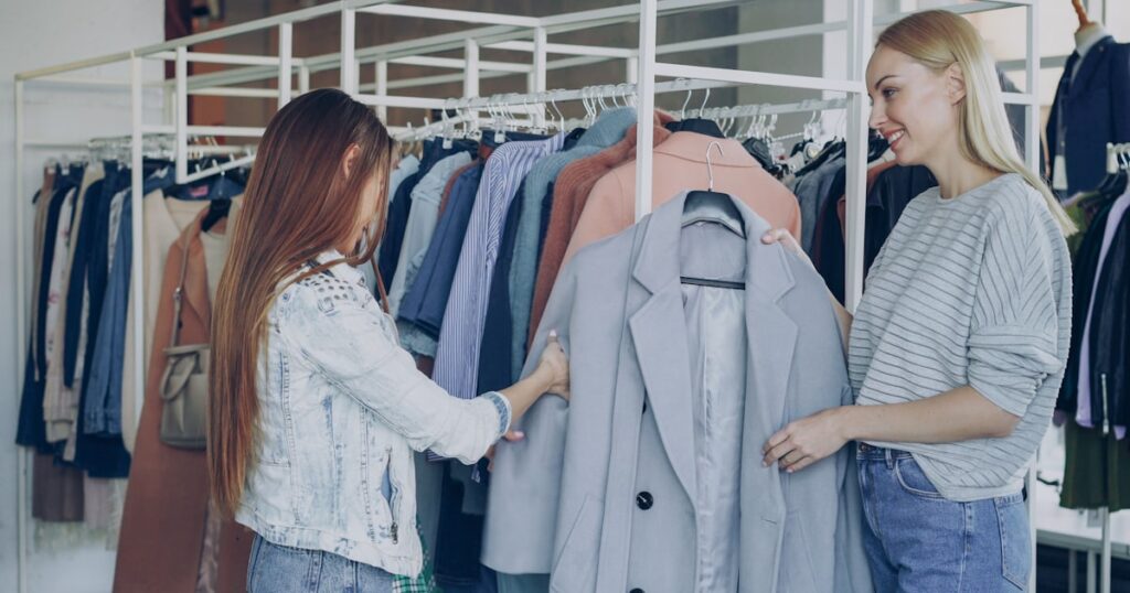 Two women browse clothing racks in a boutique.