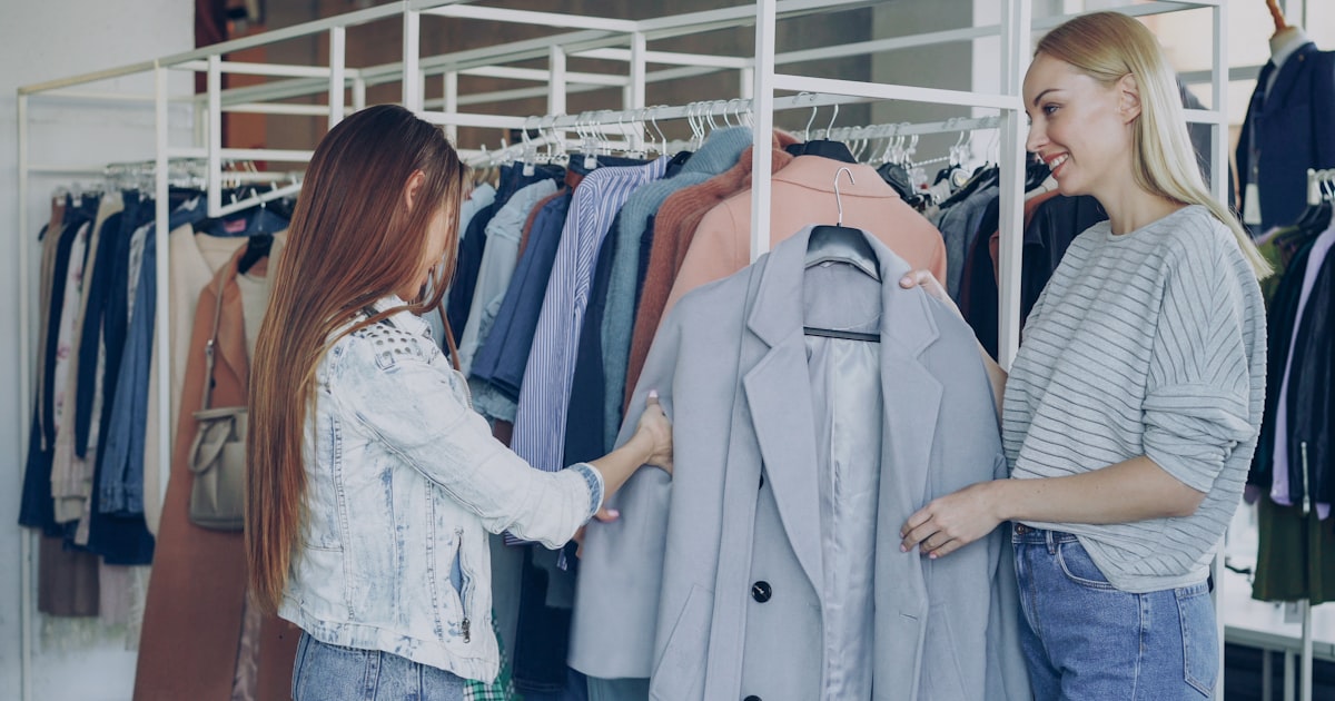 Two women browse clothing racks in a boutique.