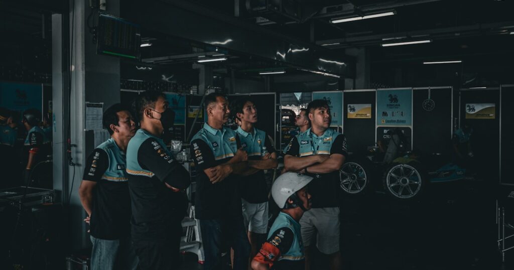 Men in uniform standing in a dark workshop.