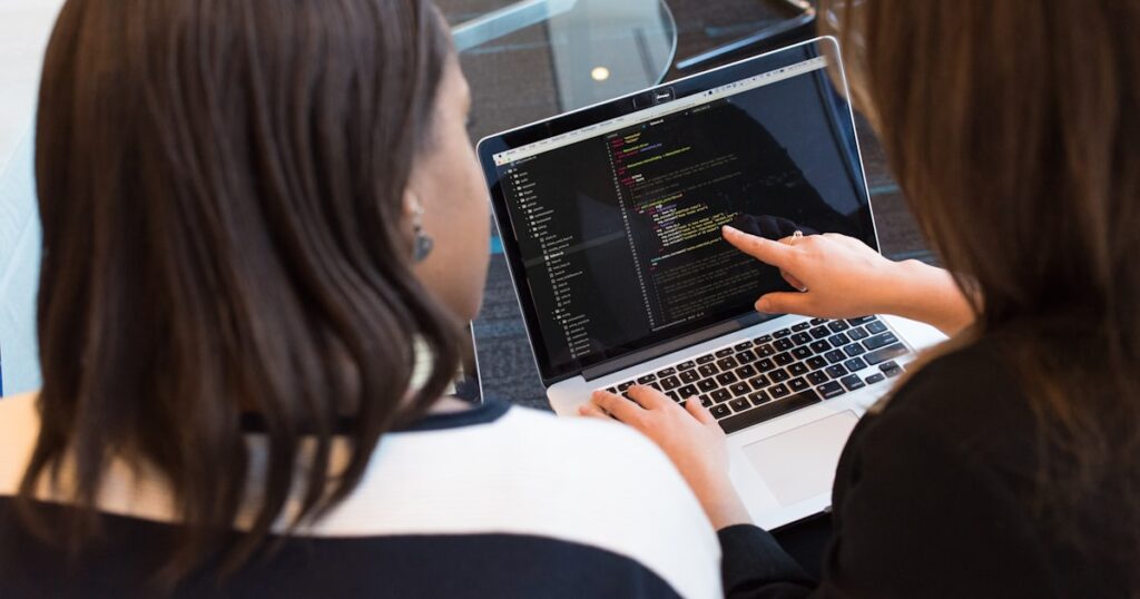 woman using MacBook Pro with person in white top