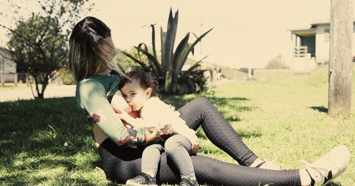 A woman sitting on the ground holding a baby