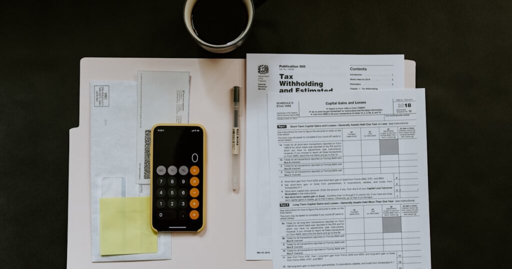 black Android smartphone near ballpoint pen, tax withholding certificate on top of white folder