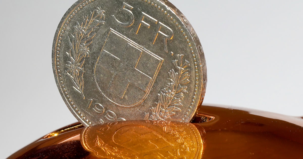 A coin being inserted into a piggy bank