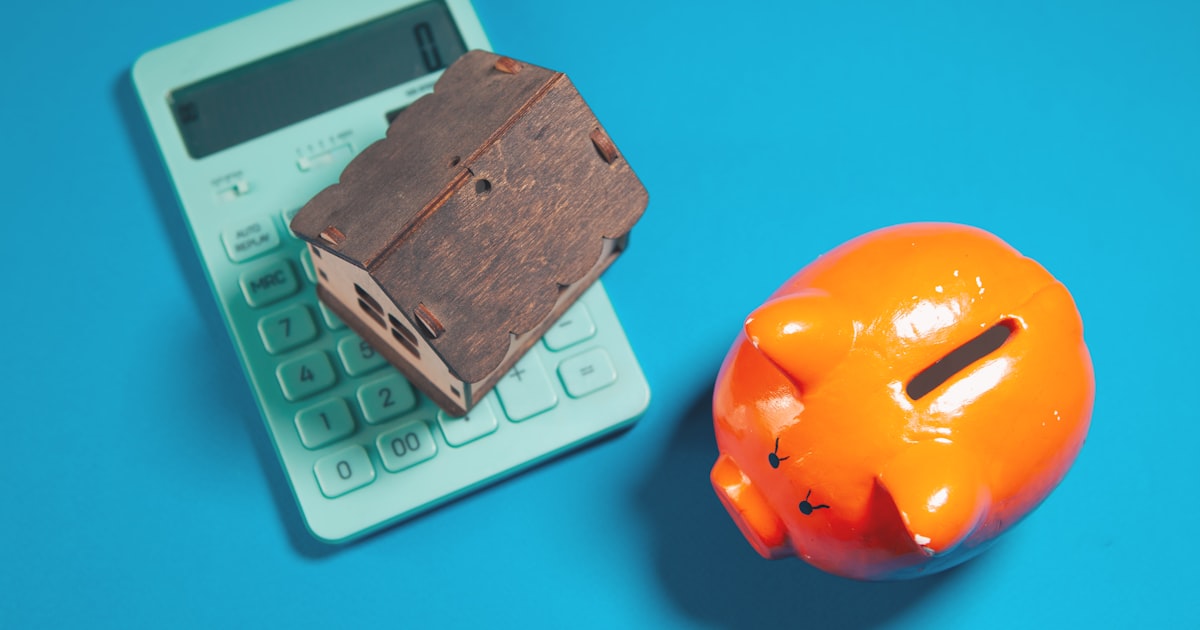 Calculator, piggy bank, and house model on blue background