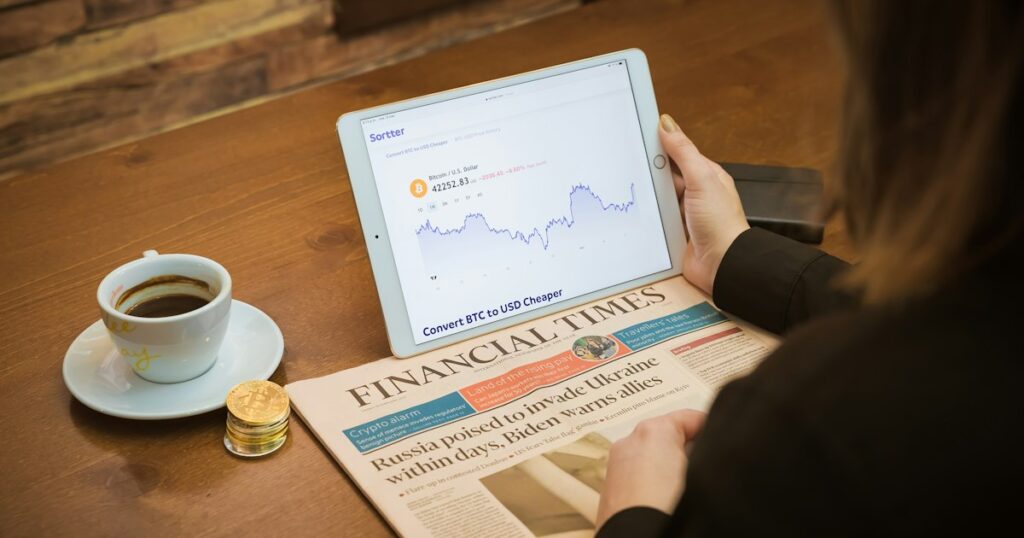 Drinking coffee in a coffee shop checking Bitcoin chart with Financial Times, from the United Kingdom, aside.
