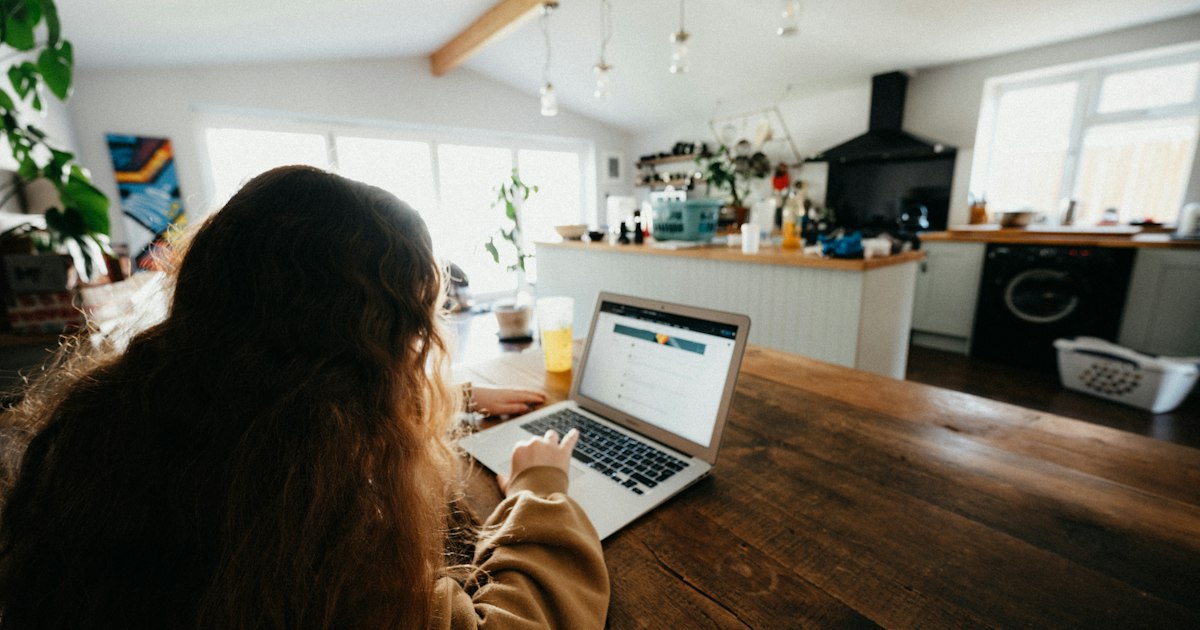 Teenage girl homelearning homework on a macbook in the family kitchen
