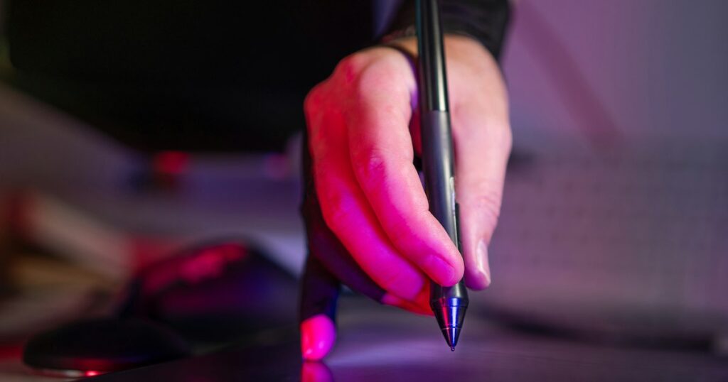 hand holding digital stylus on graphic tablet studio equipment creative tools neon light