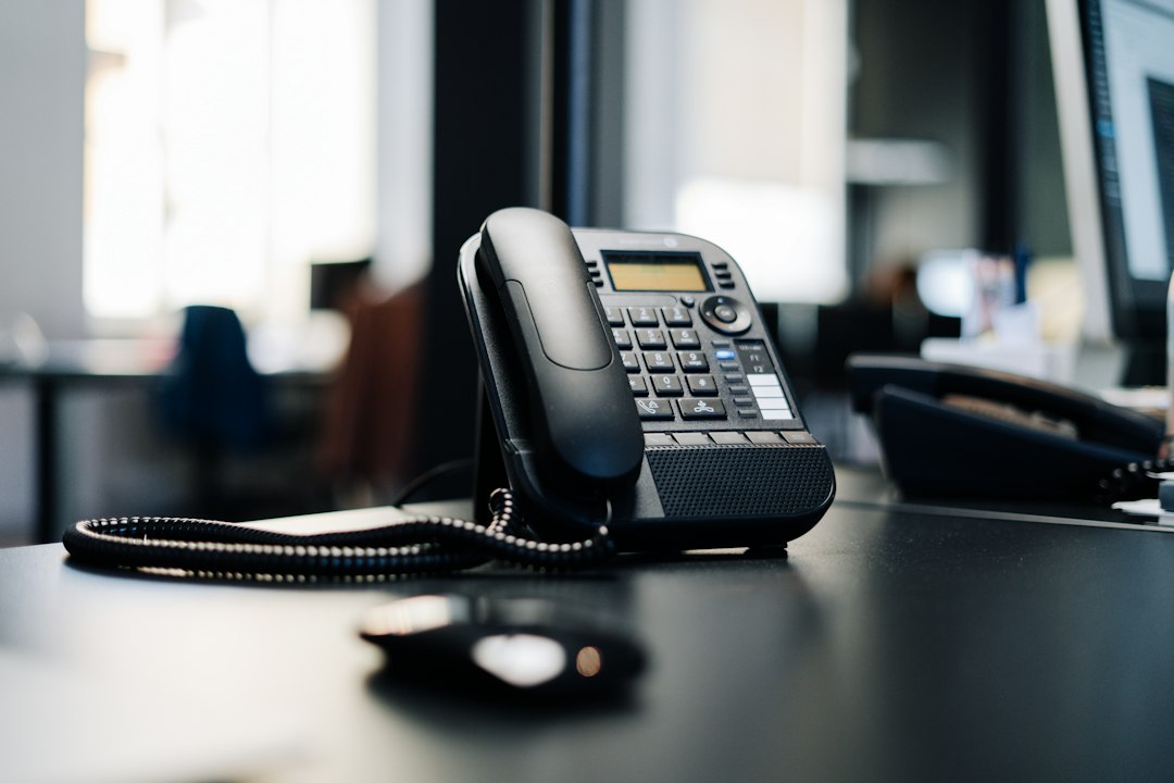 Black IP desk phone on black wooden table