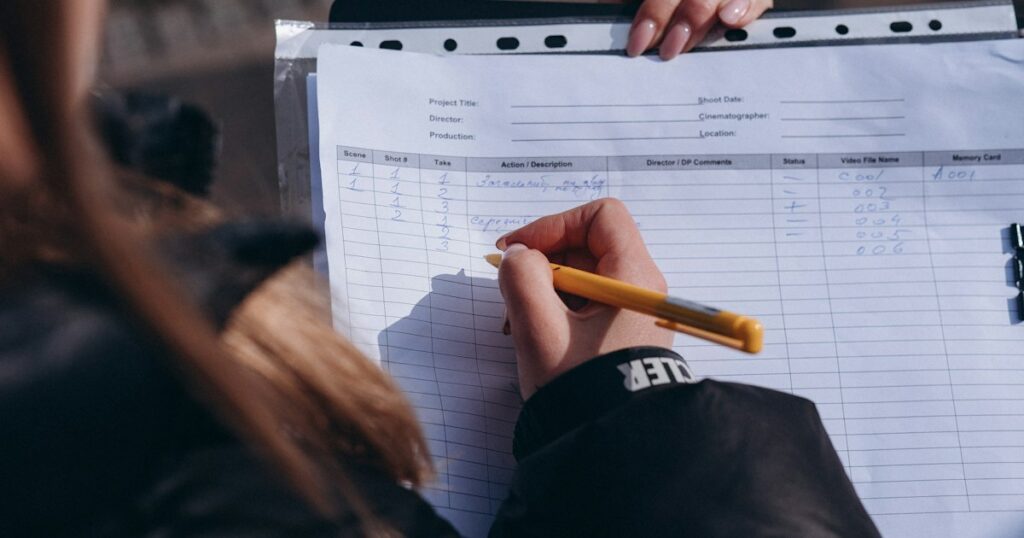 Hands filling in a paper report sheet on a film set.