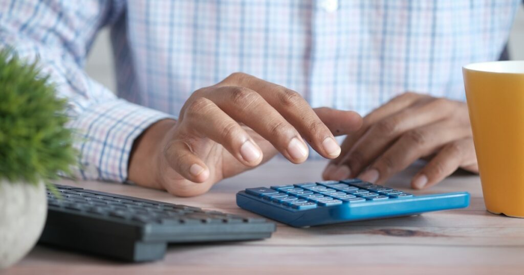 Close up of man hand using calculator.