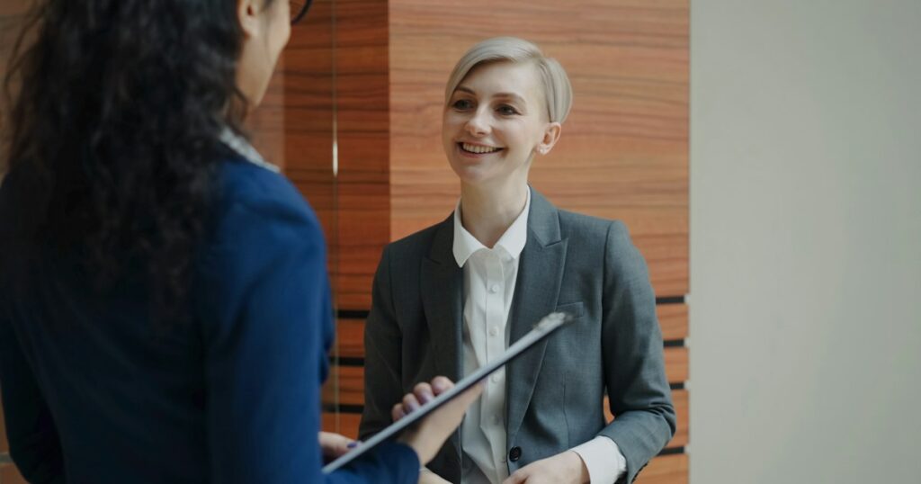 Two businesswomen colleagues talking in modern office indoors